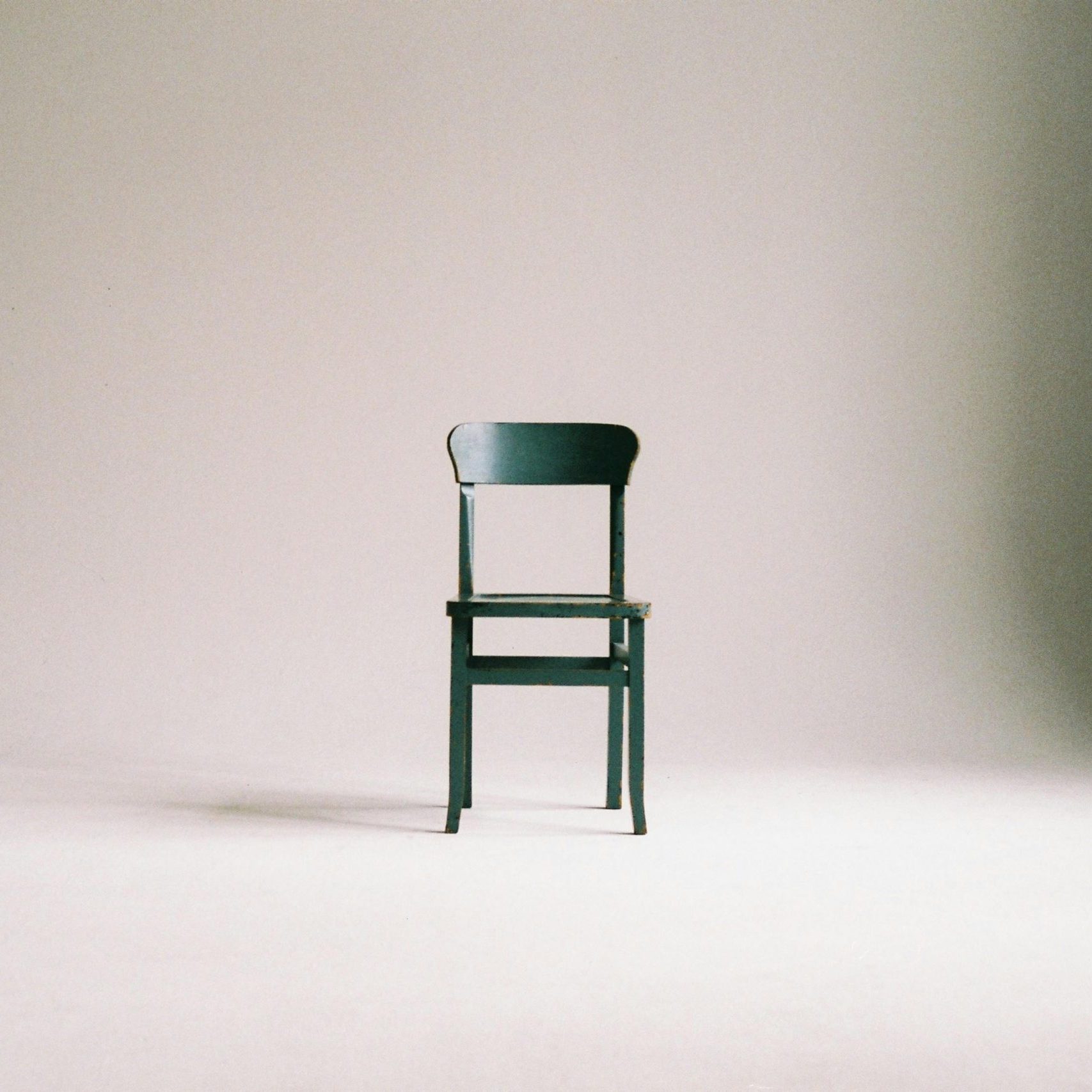 A single black chair in a minimalistic studio setting with a neutral backdrop.